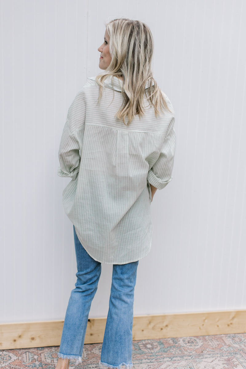 Back view of Model wearing a cream button up top with green pinstripes and long sleeves.