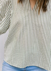 Close up of model wearing a cream top with green stripes, v-neck and 3/4 sleeve. 