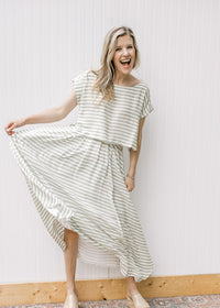 Model wearing a green and white striped set with a cropped top with boat neck and flowy skirt. 