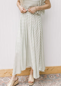 Close up of green and white stripped maxi skirt with elastic waist and pleated hem, part of set.