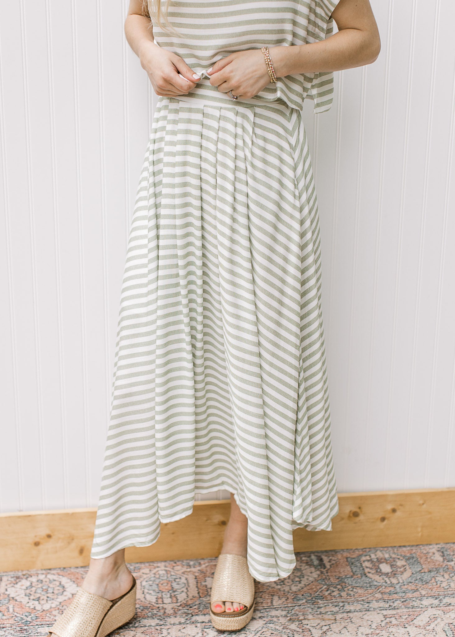 Close up of green and white stripped maxi skirt with elastic waist and pleated hem, part of set.