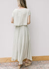 Back view of model wearing a green and white striped set with a boatneck top and flowy skirt. 