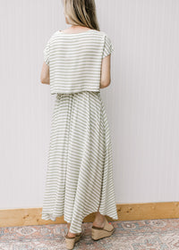 Back view of model wearing a green and white striped set with a boatneck top and flowy skirt. 