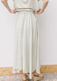 Close up of back of green and white stripped maxi skirt with elastic waist and pleated hem. 