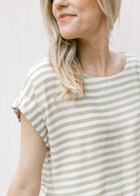 Close up of capped sleeve and boatneck on a green and white striped cropped top with skirt. 