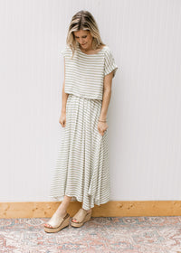 Model wearing wedges and a green and white striped set with a cropped top and flowy skirt. 