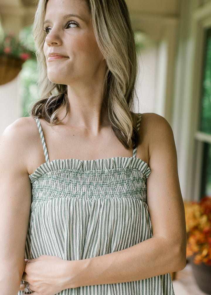 Close up of elastic neck with ruffle and spaghetti straps on a green and cream striped maxi.