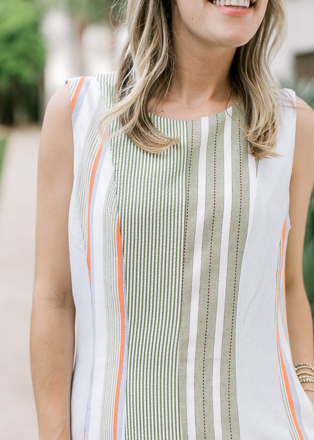 Close up of varied green stripe patterns on a cream midi with a round neck and sleeveless design.