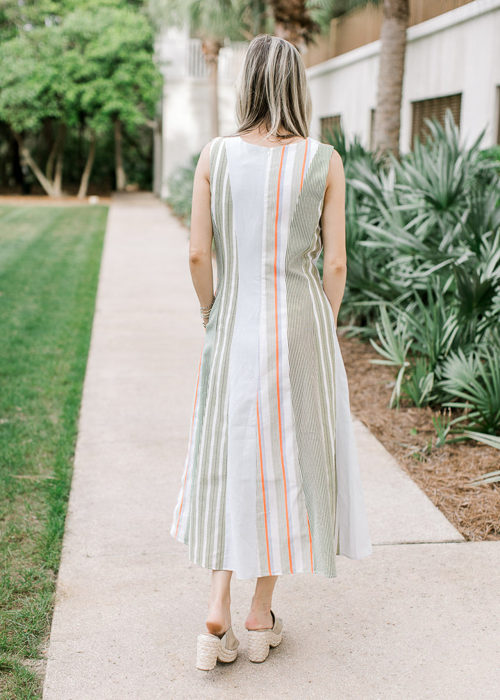 Back view of Model wearing a cream midi with a varied green stripe pattern and round neck. 