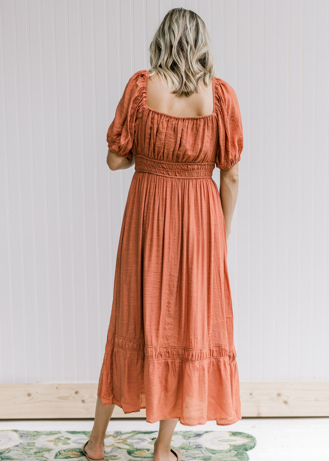 Back view of smocked band and square neck on a rust midi dress with bubble short sleeves. 