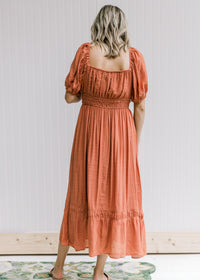 Back view of smocked band and square neck on a rust midi dress with bubble short sleeves. 
