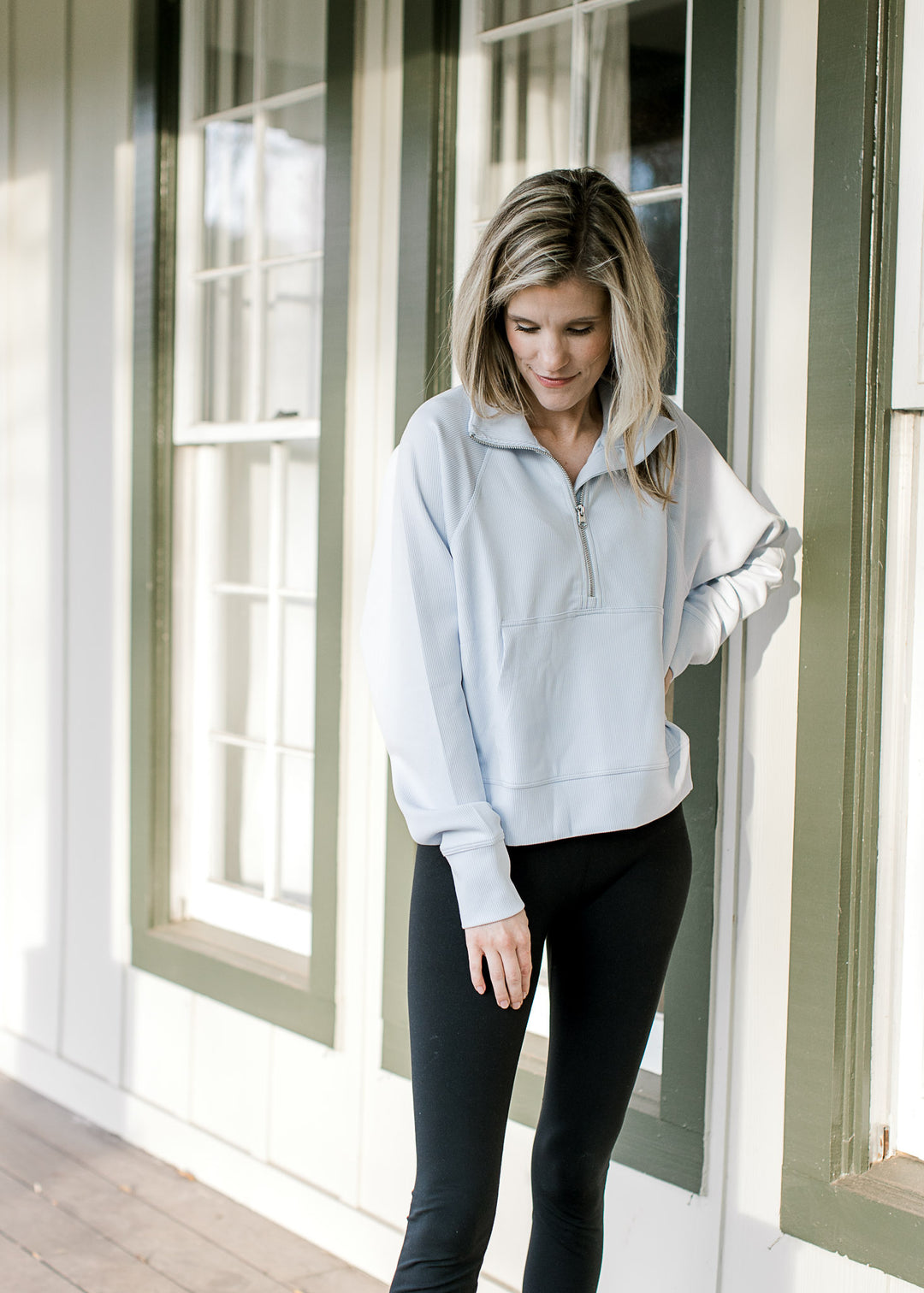 Model wearing a pale blue ribbed pullover with a quarter zip, front pouch pocket and long sleeves. 