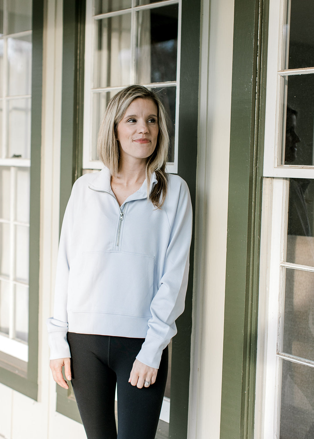 Model wearing a pale blue slightly cropped pullover with a pouch pocket and long sleeves. 