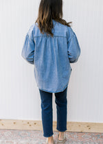 Back view of Model wearing an oversized chambray button down with long sleeves. 