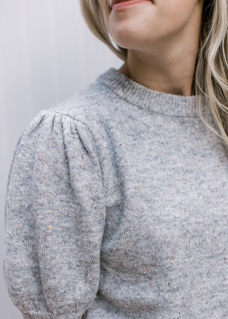 Close up of pleated shoulder and bubble short sleeves on a heather gray sweater. 