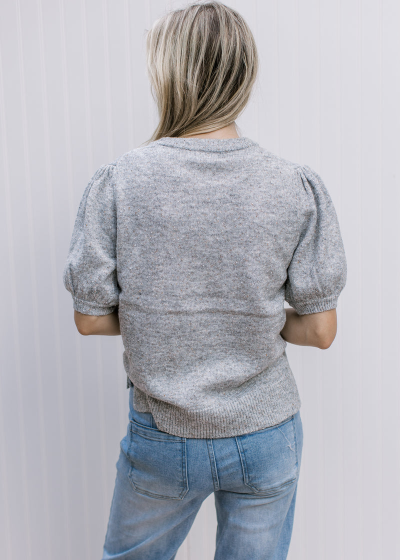 Back view of Model wearing a heather gray sweater with bubble short sleeves and pleated shoulders.