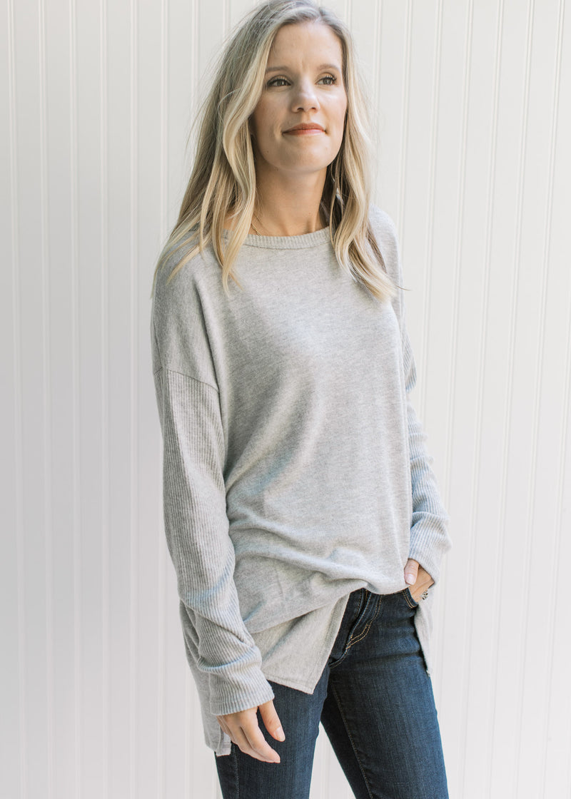 Model wearing jeans with an oversized soft gray knit top with long sleeves and a round neck. 