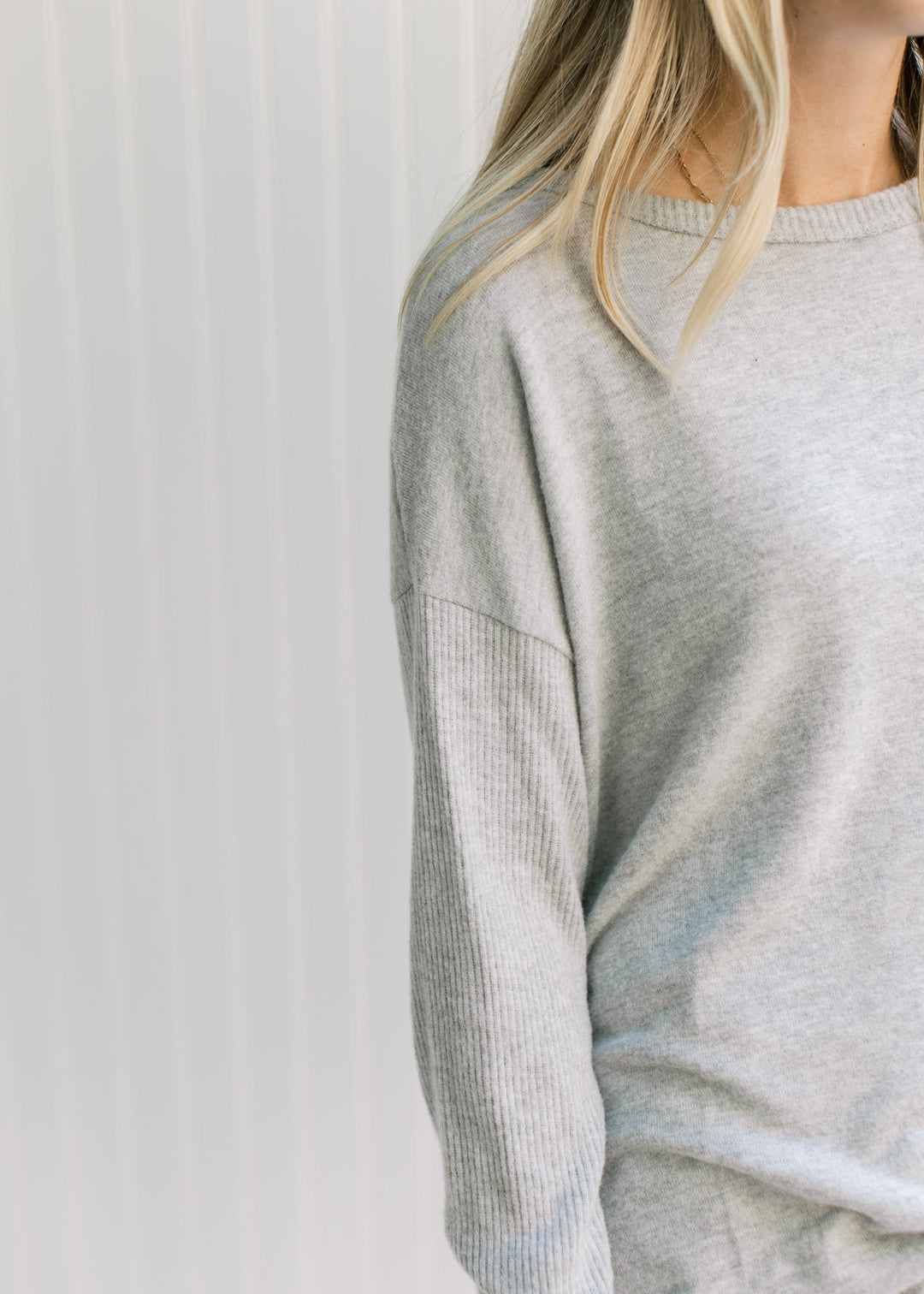 Close up of a round neck and long sleeves on a soft gray knit top with an oversized fit. 