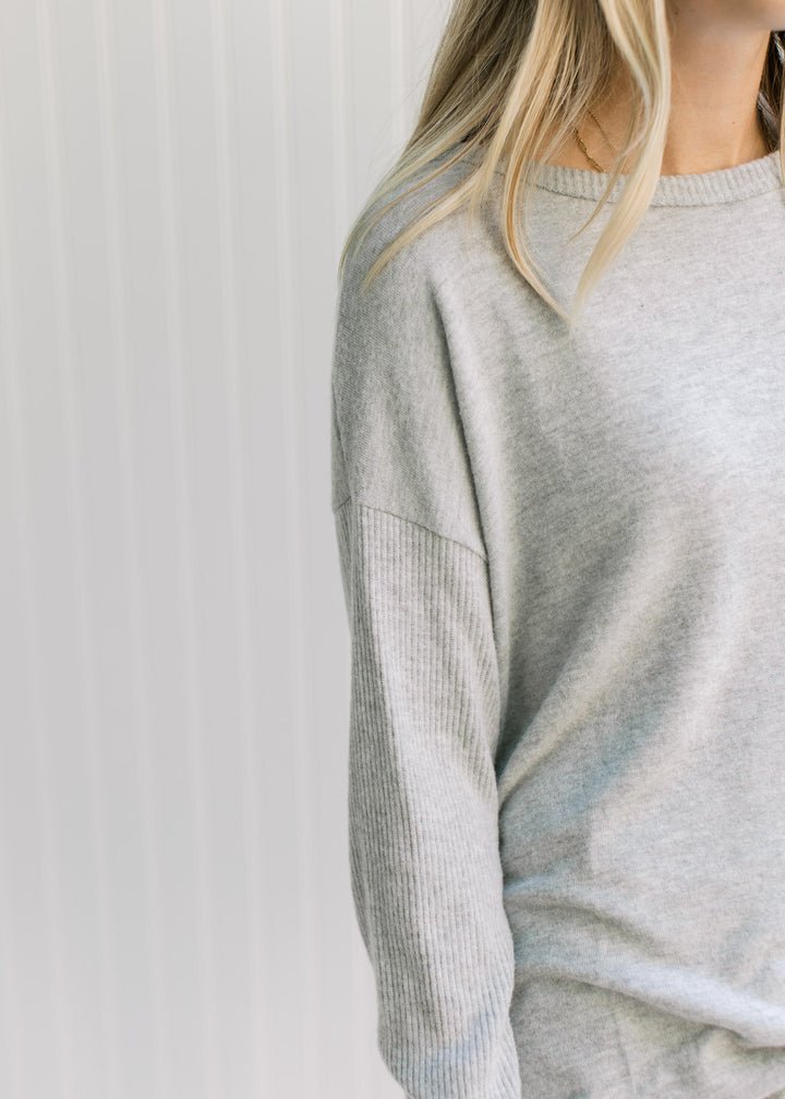 Close up of a round neck and long sleeves on a soft gray knit top with an oversized fit. 