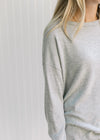 Close up of a round neck and long sleeves on a soft gray knit top with an oversized fit. 