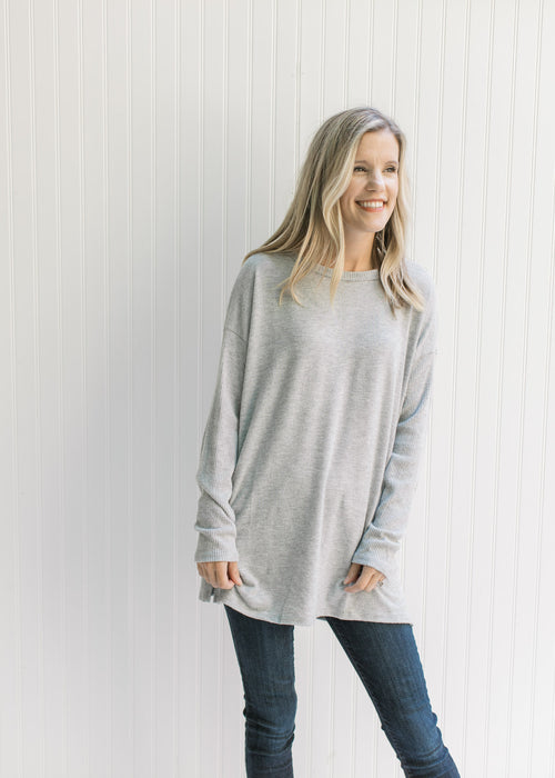 Model wearing an oversized soft gray knit top with long sleeves and a round neck. 