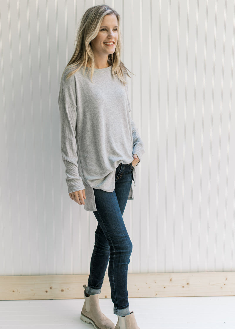 Model wearing jeans and booties with an oversized soft gray top with long sleeves and a round neck.