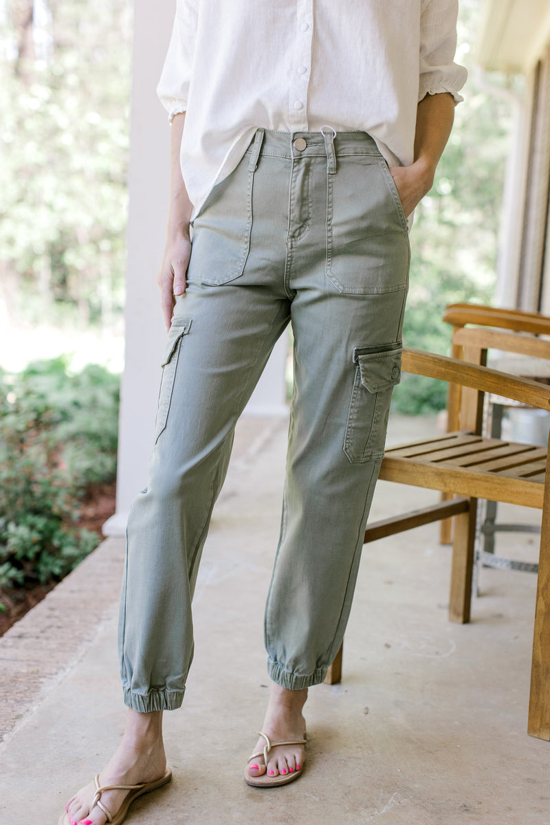 Model wearing sage high rise pants with cargo patch pockets and elastic at ankles.