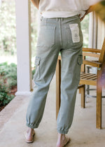 Back view of Model wearing high rise sage pants with cargo pockets and elastic ankle.