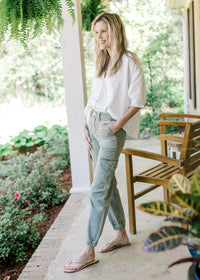 Model wearing a white top with high rise sage pants with cargo pockets and elastic ankle.