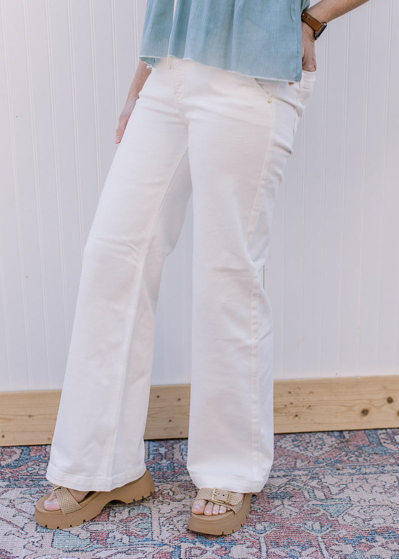 Model wearing sandals and white, wide leg pants with a high rise fit, stretch and side slit pockets.