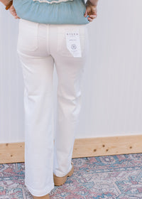 Back view of Model wearing white, wide leg pants with a high rise fit and side slit pockets.