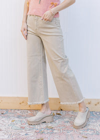 Model wearing khaki high rise jeans with a cropped fit, frayed hem and wide legs. 