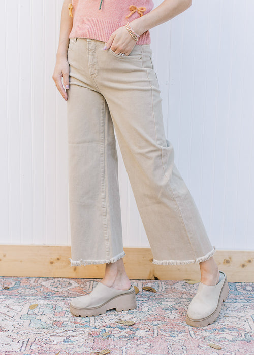 Model wearing khaki high rise jeans with a cropped fit, frayed hem and wide legs. 