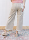 Back view of Model wearing khaki high rise jeans with a cropped fit, frayed hem and wide legs. 