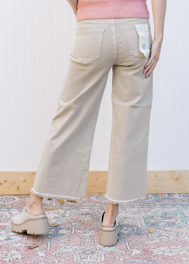 Back view of Model wearing khaki high rise jeans with a cropped fit, frayed hem and wide legs. 