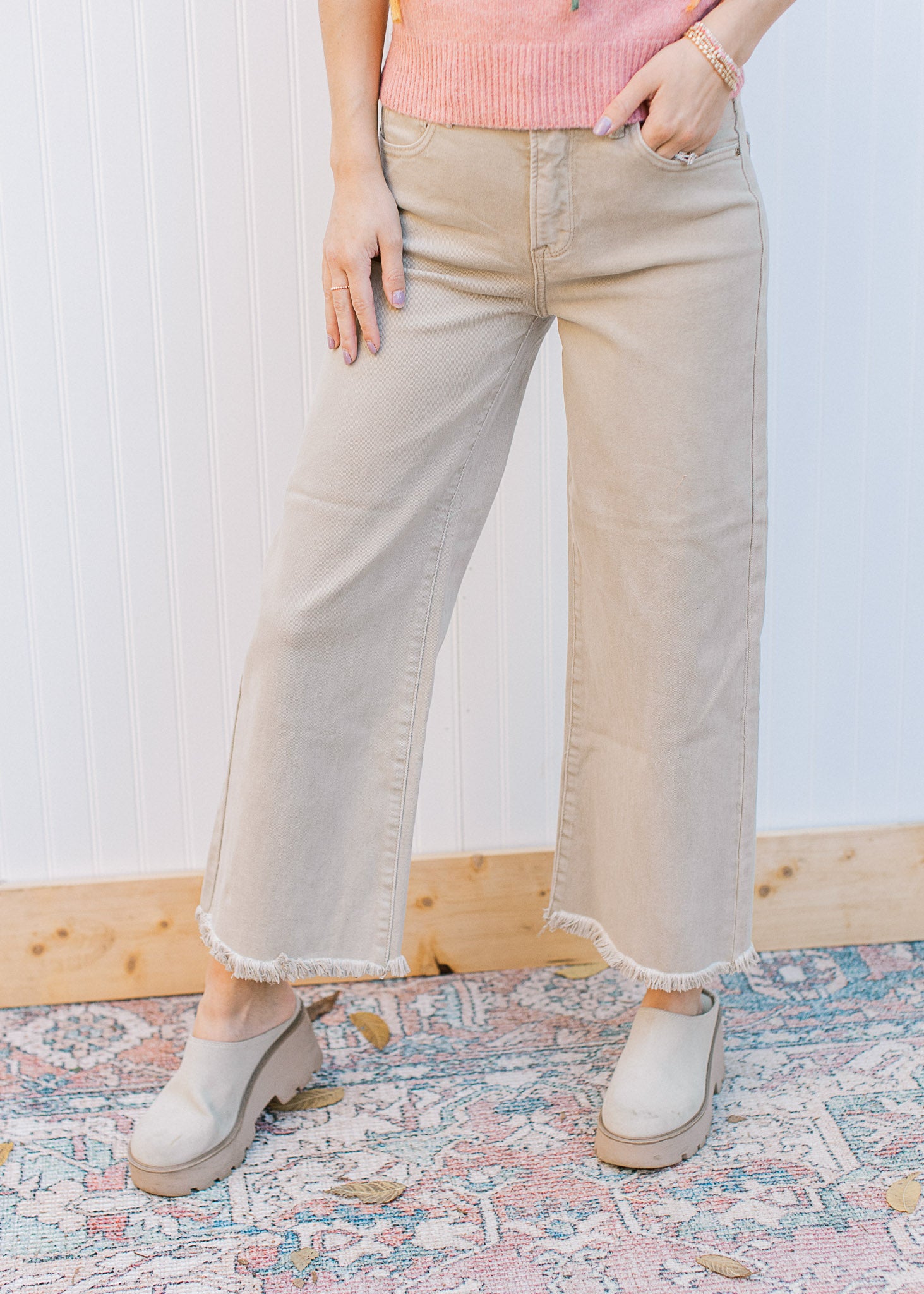 Model wearing mules with khaki high rise jeans with a cropped fit, frayed hem and wide legs. 