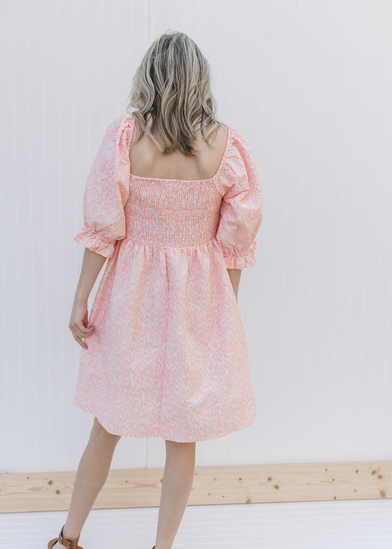 Back view of pink dress with pink microfloral, smocked back and a square neckline. 