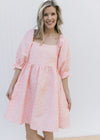 Model wearing a pink above the knee dress with a soft pink textured microfloral and 3/4 poet sleeve.