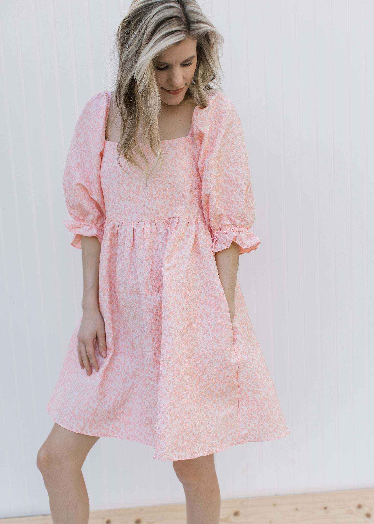 Model wearing a pink above the knee dress with a soft pink textured microfloral and a square neck.