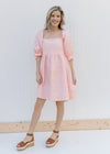 Model wearing heels and a pink dress with a soft pink microfloral pattern and a square neck.
