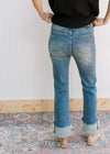 Back view of Model wearing high waisted jeans with a faded wash, bootcut and a raw hem.