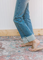 Close up of raw hem on a model wearing high waisted jeans with a faded wash.