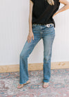 Model wearing high waisted jeans with a faded wash, double button and a raw hem.