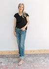 Model wearing a black top with high waisted jeans with a faded wash, bootcut and a raw hem.