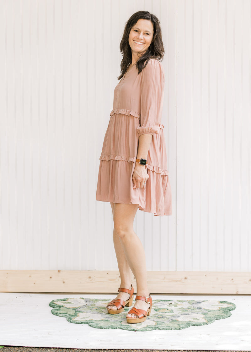 Model wearing heels with a blush above the knee dress with 3/4 bubble sleeves and v-neck. 