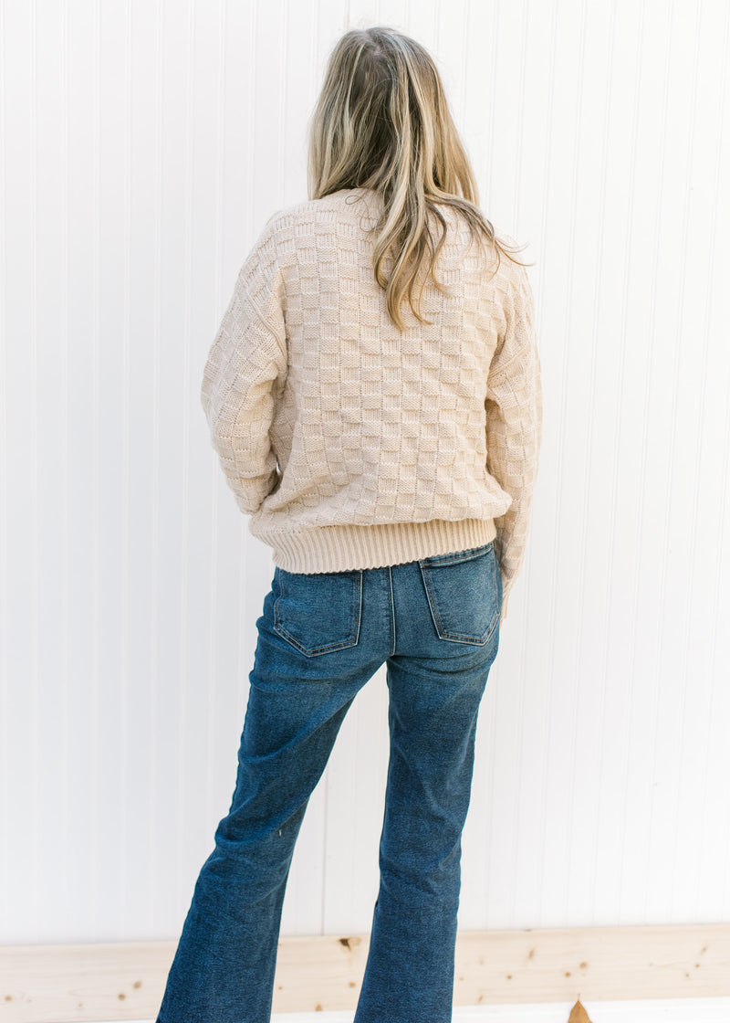 Back view of Model wearing a tan sweater with checkered knit, long sleeves and a round neck. 