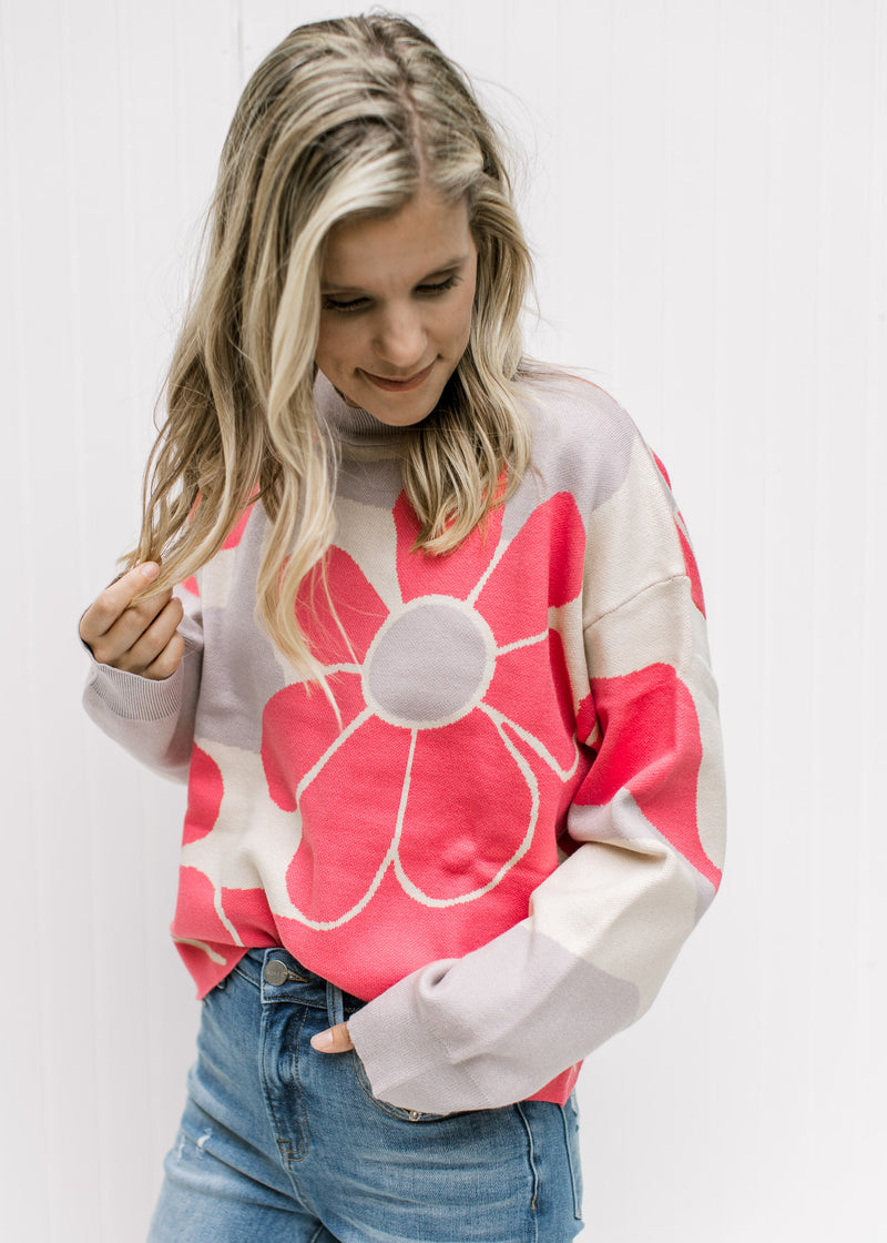 Model wearing a cream sweater with coral flowers with long sleeves and a slightly cropped fit.