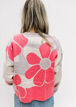 Back view of Model wearing a cream sweater with coral flowers with long sleeves and a cropped fit.