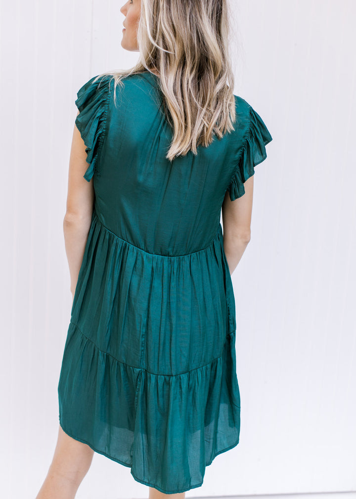 Back view of Model wearing a hunter green above the knee dress with a ruffle cap sleeve.