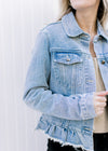 Model wearing a light denim jacket with a button closure, ruffled raw hem and long sleeves. 